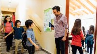Elementary teacher greets students in the morning outside of the the classroom
