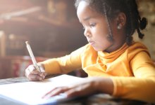 Profile of little girl writing at home.